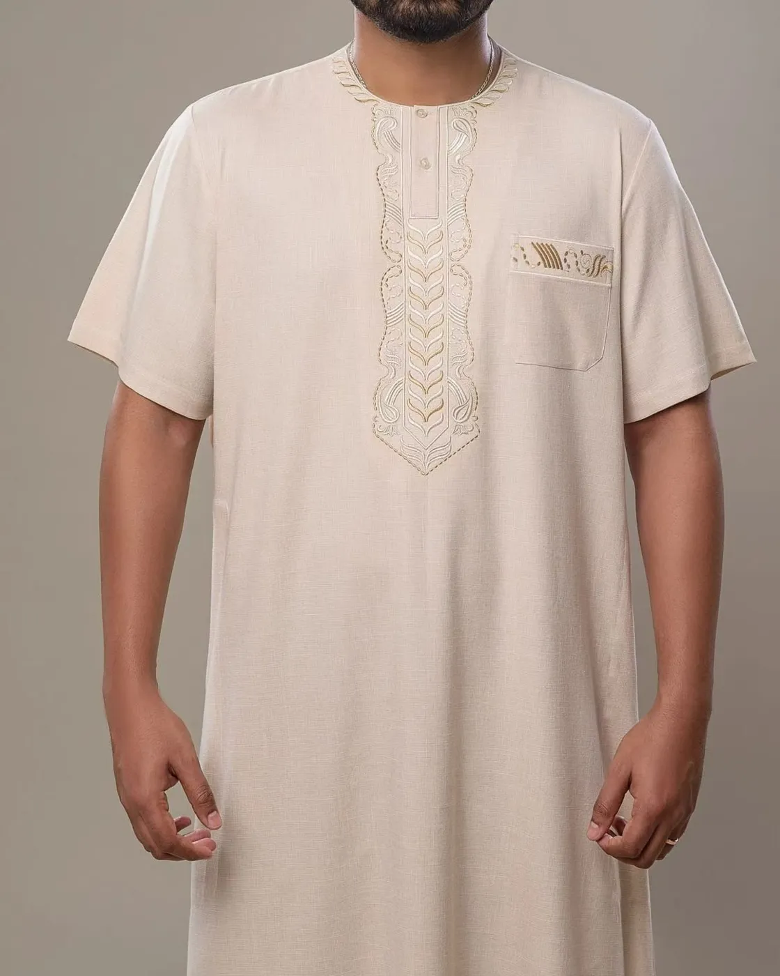 Man wearing a cream short-sleeve thobe with ivory and gold neckline embroidery
