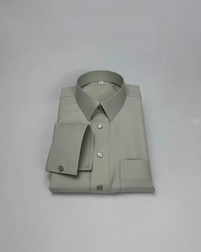 Folded pale sage dress shirt showing a pointed collar, a French cuff and engraved silver-tone buttons