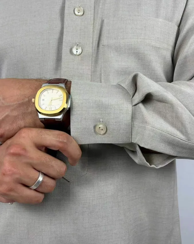 Detail of a beige linen-blend thobe cuff and buttoned placket worn on the wrist